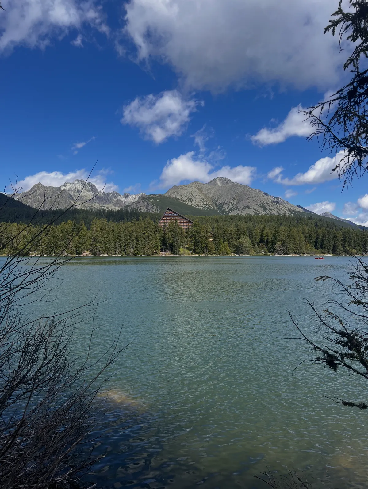 A clear mountain lake ringed by pines under the Tatras